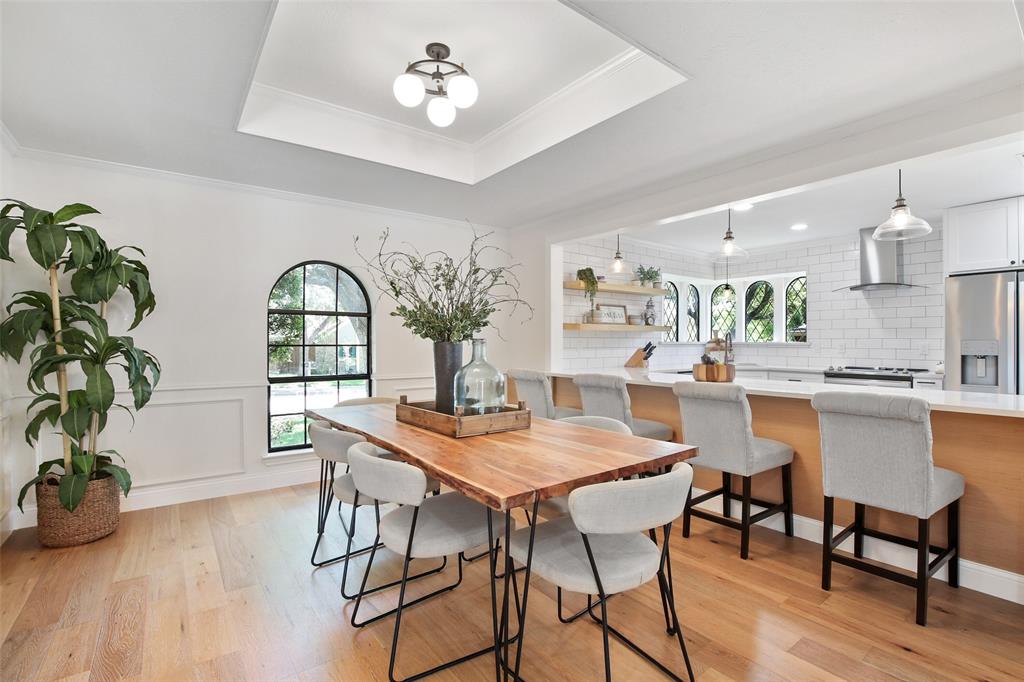 Open concept kitchen and dining space with warm flooring and white cabinetry